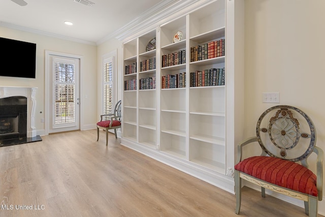 sitting room featuring baseboards, visible vents, wood finished floors, crown molding, and a high end fireplace