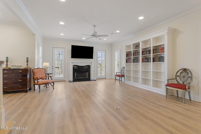 sitting room with recessed lighting, light wood-type flooring, a fireplace, and crown molding