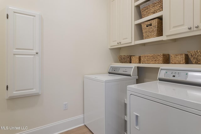 laundry room featuring cabinet space, washing machine and dryer, baseboards, and light wood finished floors