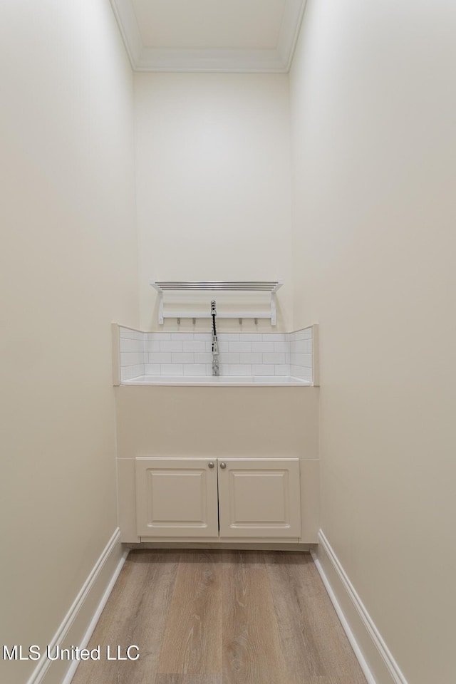 interior space featuring light wood finished floors, baseboards, and crown molding