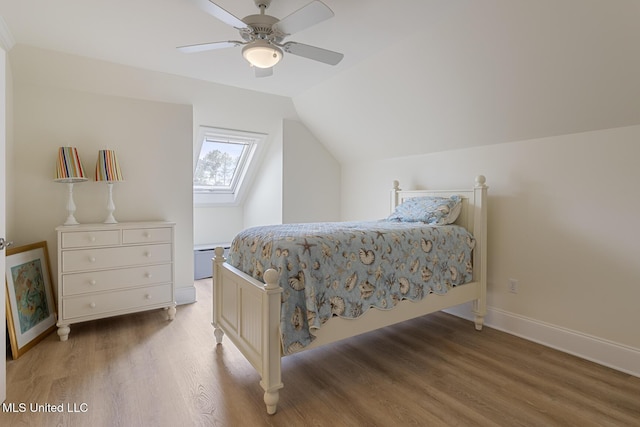 bedroom featuring light wood-style floors, ceiling fan, baseboards, and lofted ceiling with skylight