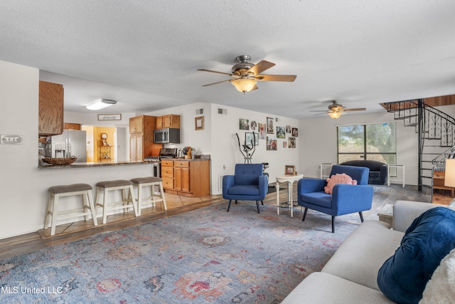 living room featuring a textured ceiling, hardwood / wood-style flooring, and ceiling fan