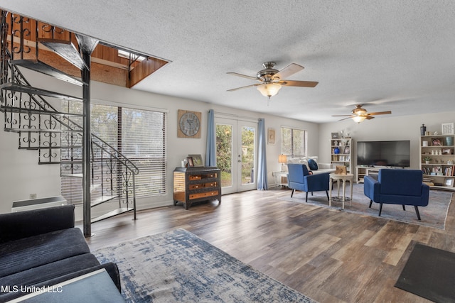 living room with ceiling fan, french doors, hardwood / wood-style floors, and a textured ceiling