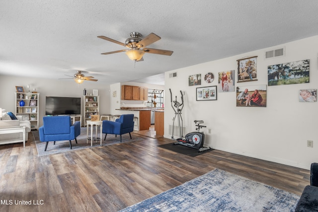 living room with ceiling fan, dark hardwood / wood-style flooring, and a textured ceiling