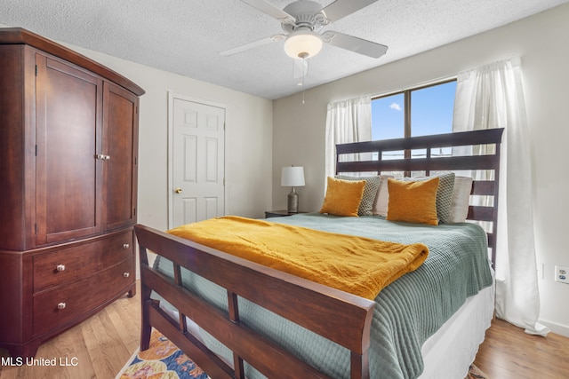 bedroom featuring ceiling fan, light hardwood / wood-style flooring, and a textured ceiling