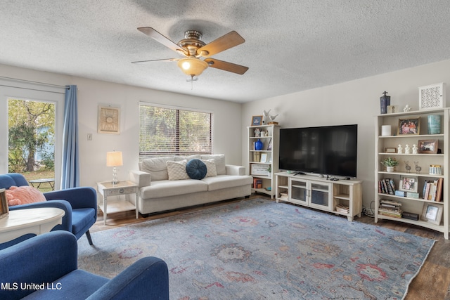 living room featuring a textured ceiling, ceiling fan, and dark wood-type flooring