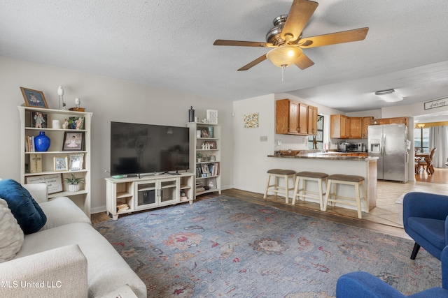 living room featuring a textured ceiling, light hardwood / wood-style floors, and ceiling fan