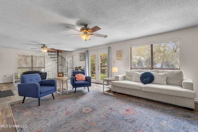 living room featuring french doors, ceiling fan, hardwood / wood-style floors, and a textured ceiling