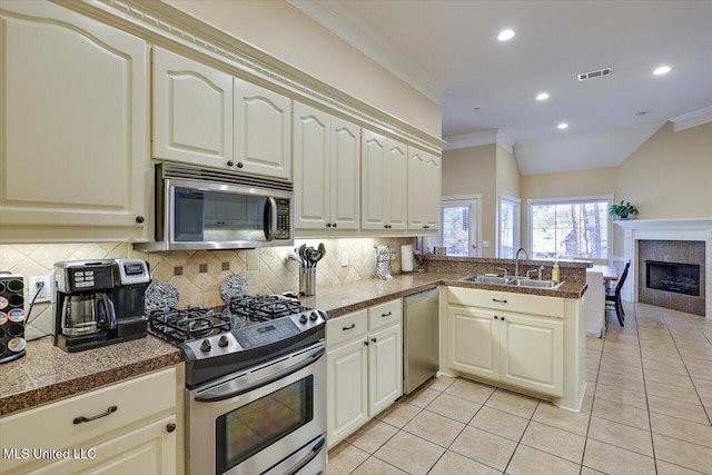 kitchen with sink, backsplash, ornamental molding, kitchen peninsula, and stainless steel appliances