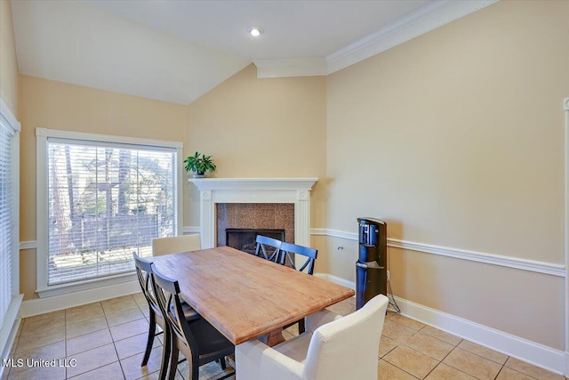 tiled dining area with a fireplace, ornamental molding, and vaulted ceiling