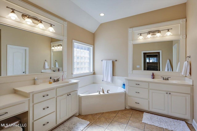 bathroom featuring tile patterned flooring, vanity, vaulted ceiling, and a tub to relax in