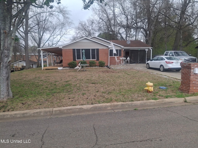 view of front of home featuring brick siding, driveway, an attached carport, and a front lawn