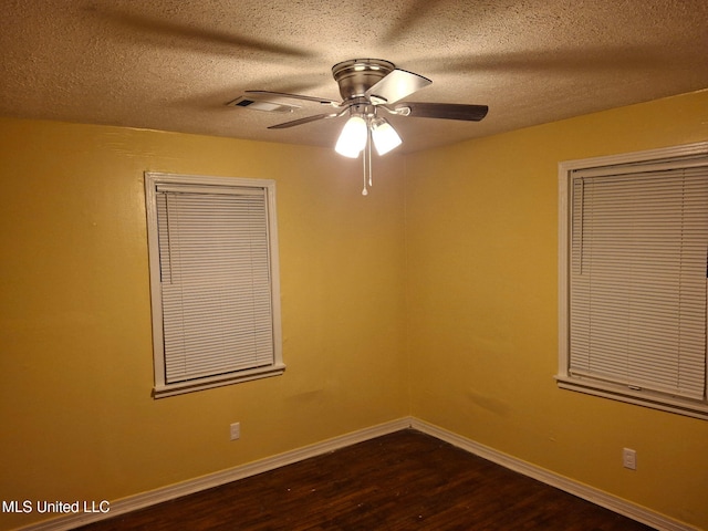 spare room with visible vents, ceiling fan, baseboards, a textured ceiling, and dark wood-style flooring