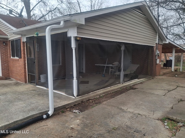 view of side of property with brick siding and a sunroom