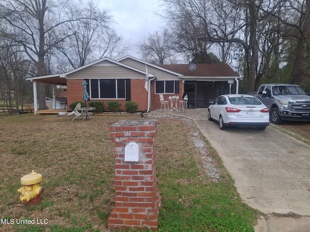 view of front of house with an attached carport, a front yard, brick siding, and driveway