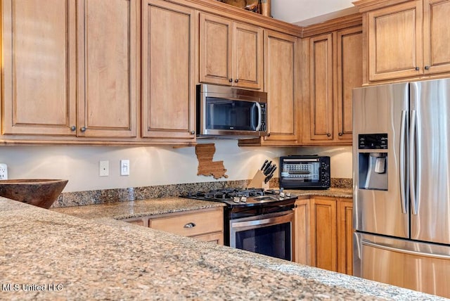 kitchen featuring stainless steel appliances and light stone countertops