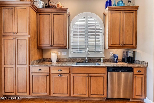 kitchen with stainless steel dishwasher, sink, and dark stone counters