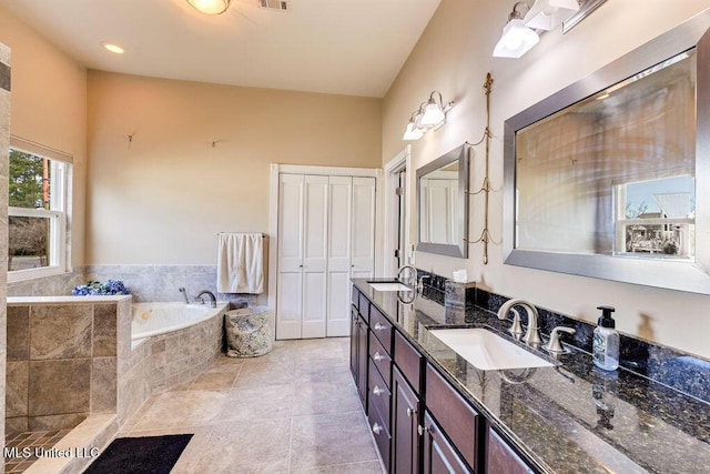 bathroom with tiled bath, tile patterned flooring, and vanity