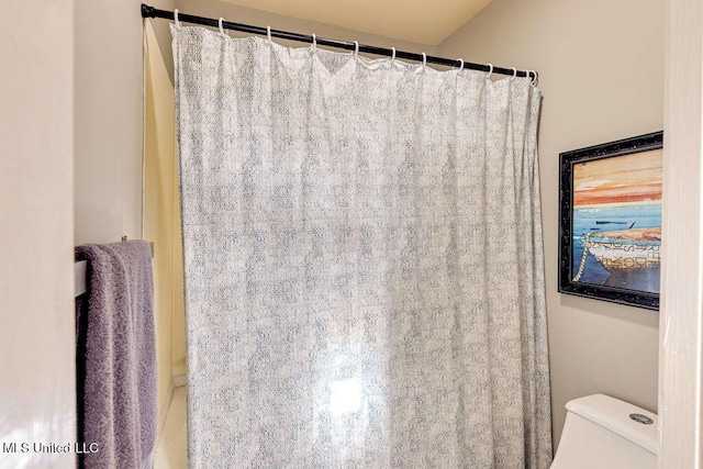 bathroom featuring toilet and curtained shower