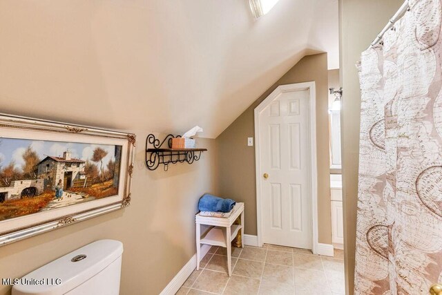 bathroom with toilet, tile patterned flooring, and vaulted ceiling