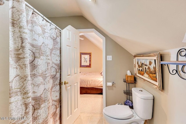 bathroom with vaulted ceiling, tile patterned floors, and toilet