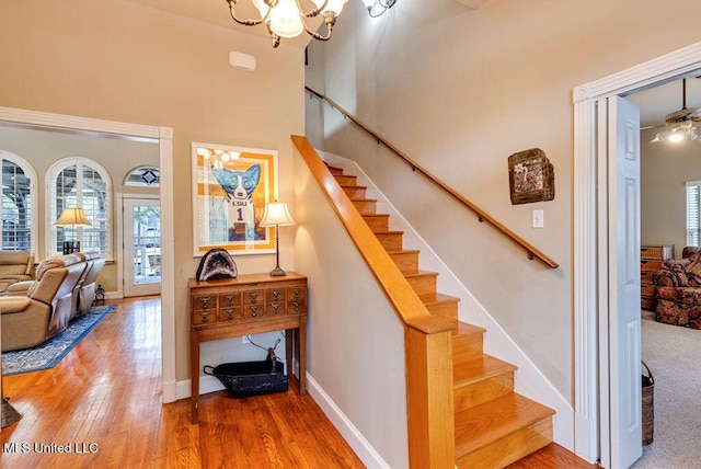 stairs with an inviting chandelier and hardwood / wood-style floors