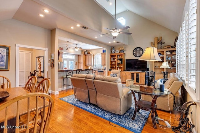 living room featuring lofted ceiling, ceiling fan, and light hardwood / wood-style flooring