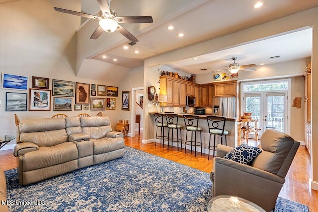 living room with light wood-type flooring, ceiling fan, french doors, and lofted ceiling with beams