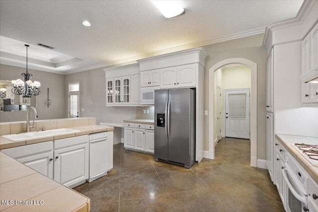 kitchen featuring white appliances, tile counters, visible vents, glass insert cabinets, and a sink