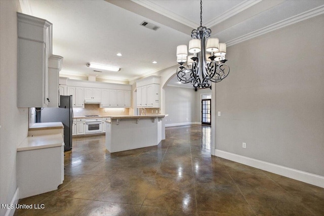 kitchen featuring a breakfast bar area, visible vents, ornamental molding, under cabinet range hood, and baseboards