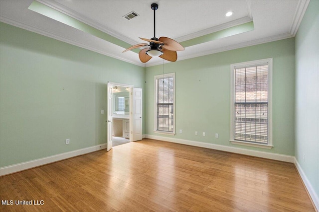 unfurnished room featuring light wood-style floors, a wealth of natural light, a raised ceiling, and visible vents