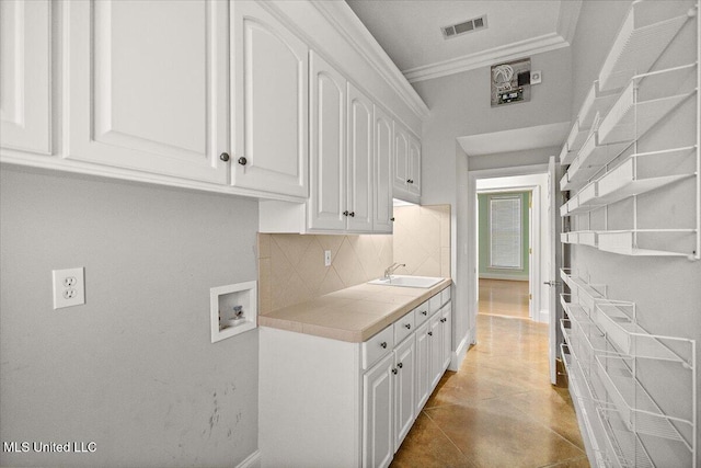 kitchen with tasteful backsplash, visible vents, crown molding, white cabinetry, and a sink