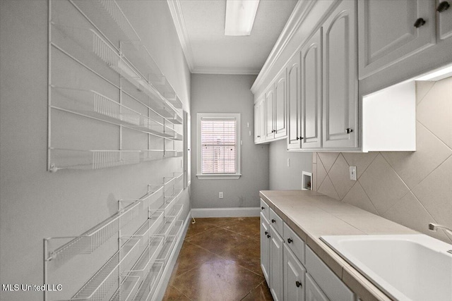 interior space featuring a sink, white cabinets, light countertops, ornamental molding, and decorative backsplash