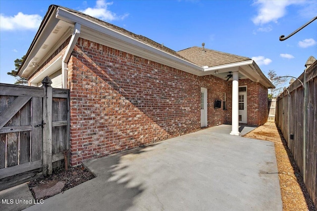 view of side of property with a gate, brick siding, a patio, and a fenced backyard