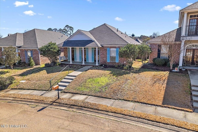 view of front facade featuring covered porch, brick siding, and a front yard