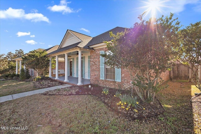 greek revival inspired property featuring ceiling fan, roof with shingles, fence, a porch, and brick siding