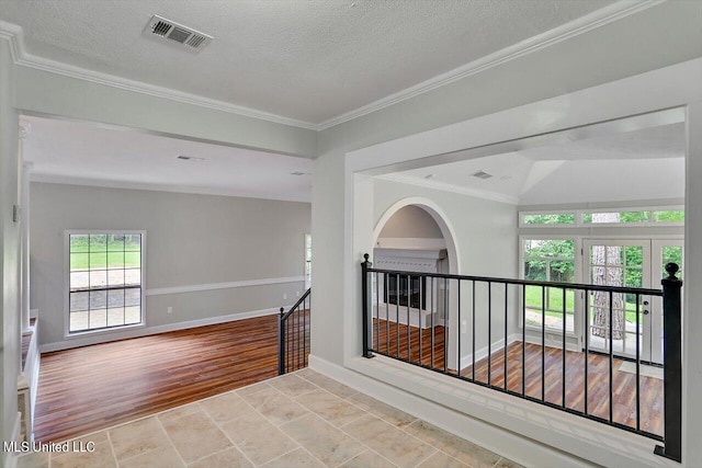 hall featuring light hardwood / wood-style floors, lofted ceiling, a textured ceiling, and ornamental molding