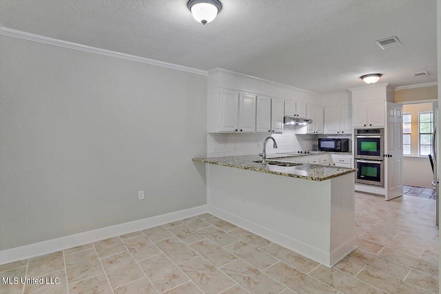 4441 Wedgewood St, Jackson, MS 39211 - kitchen featuring under cabinet range hood, visible vents, stainless steel double oven, black microwave, and a peninsula
