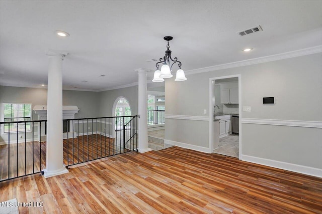 unfurnished room featuring light hardwood / wood-style floors, a notable chandelier, ornamental molding, and a wealth of natural light