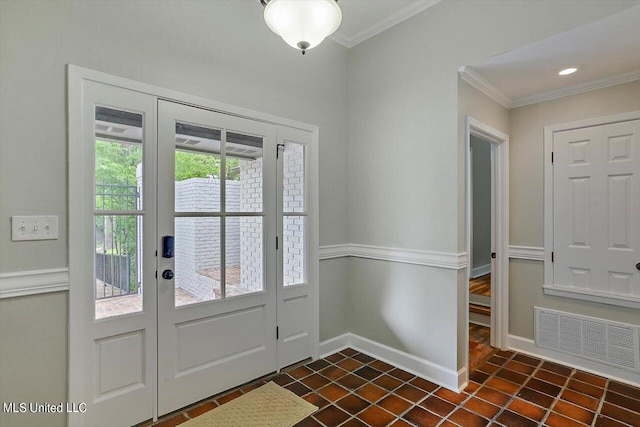 entryway with ornamental molding and dark tile patterned floors