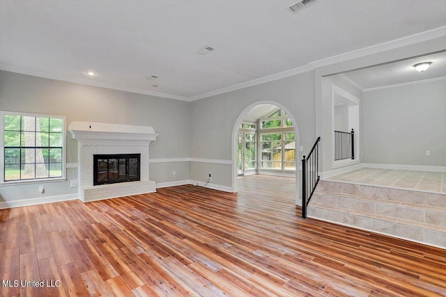 4441 Wedgewood St, Jackson, MS 39211 - unfurnished living room featuring light wood-style flooring, a brick fireplace, stairway, visible vents, and arched walkways