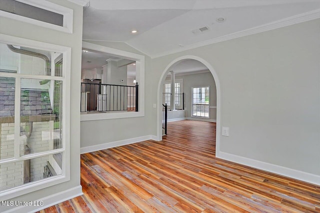 unfurnished room with ornamental molding, vaulted ceiling, and light hardwood / wood-style flooring