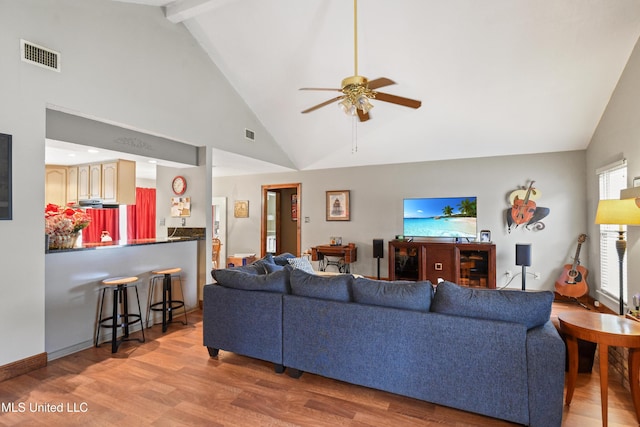 living room with vaulted ceiling with beams, ceiling fan, and light hardwood / wood-style floors