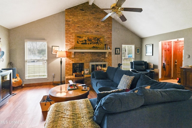 living room featuring vaulted ceiling with beams, ceiling fan, a fireplace, and hardwood / wood-style flooring