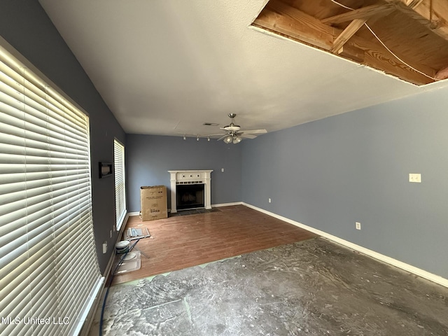 unfurnished living room with ceiling fan, a fireplace, and baseboards