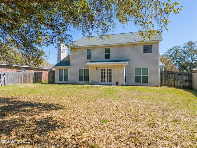 back of house with french doors, a lawn, a fenced backyard, and a chimney