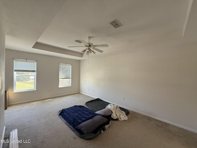 unfurnished room featuring a tray ceiling, baseboards, visible vents, and carpet flooring