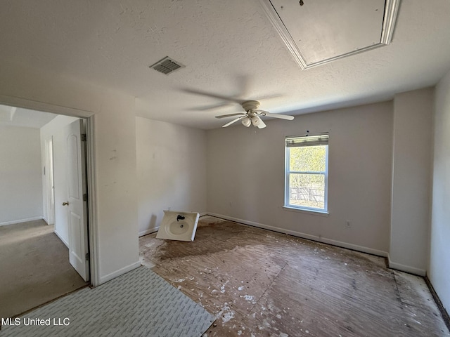 spare room featuring visible vents, baseboards, ceiling fan, attic access, and a textured ceiling