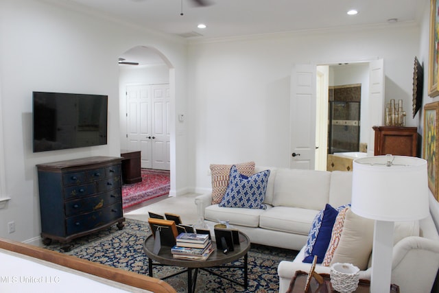 carpeted living room with arched walkways, ceiling fan, ornamental molding, and recessed lighting