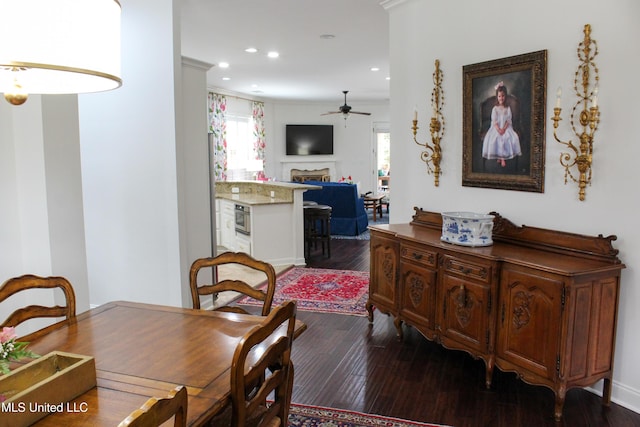 dining space featuring dark wood-style flooring, crown molding, a fireplace, recessed lighting, and ceiling fan